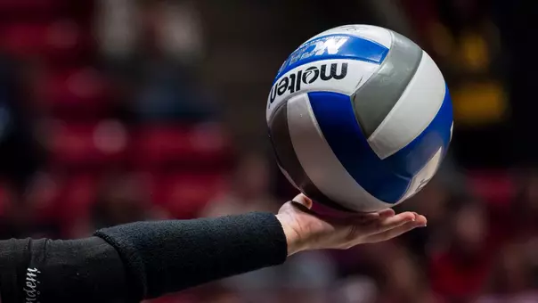 A women's volleyball player holding a volleyball getting ready to serve