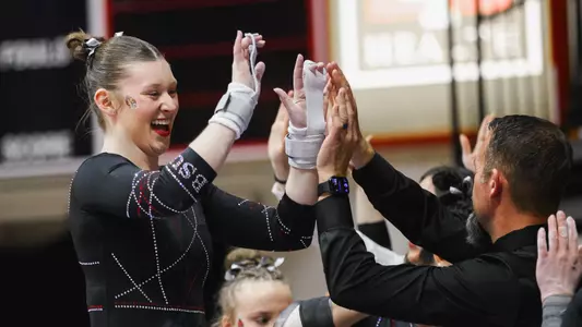 Ashley Szymanski celebrating her 9.950 on bars on Alumni and Sports Crossover Day