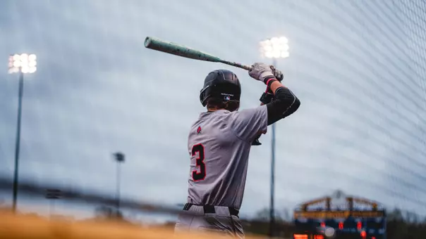 Brett Griffiths in a grey Ball State baseball uniform holding a bat and practicing his swing on Saturday, April 18 at Kent State.