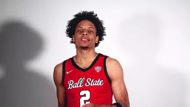 Javion Guy-King in a red Ball State uniform at a photo shoot with a white backdrop.