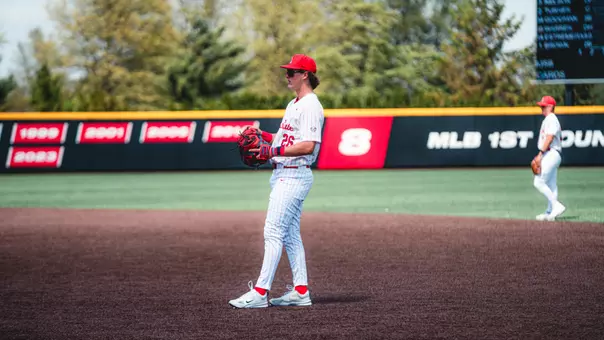 Jack Bakus in a white Ball State baseball uniform playing first base.