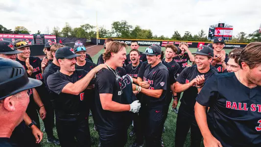 Jack Bakus in a black Ball State baseball uniform celebrating with teammates after hitting a walk-off home run