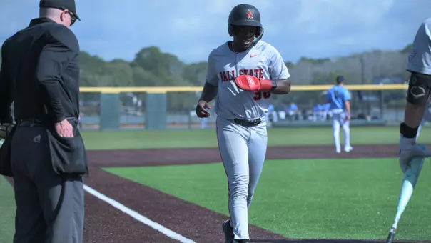 Kenskey Thomas in a grey uniform crossing home plate