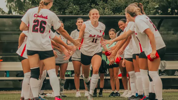 Ainsley Schaufele in a white Ball State soccer jersey runs out to the field as she gets announced for the starting lineup in an exhibition vs Indiana State