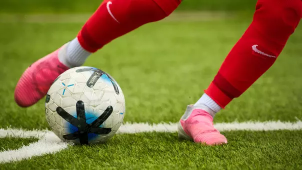 Soccer ball being kicked by a player in red socks
