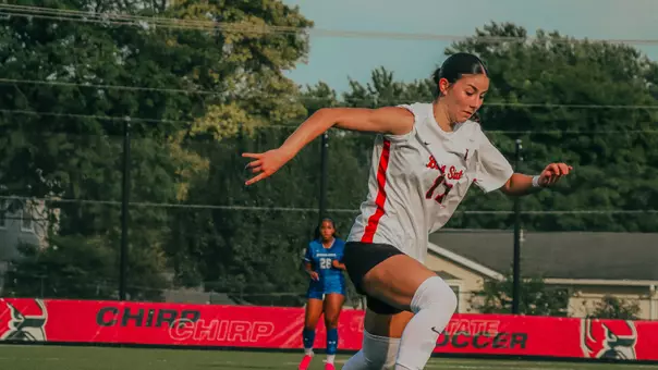 Mary Jane Keller in a white Ball State soccer jersey dribbling the soccer ball