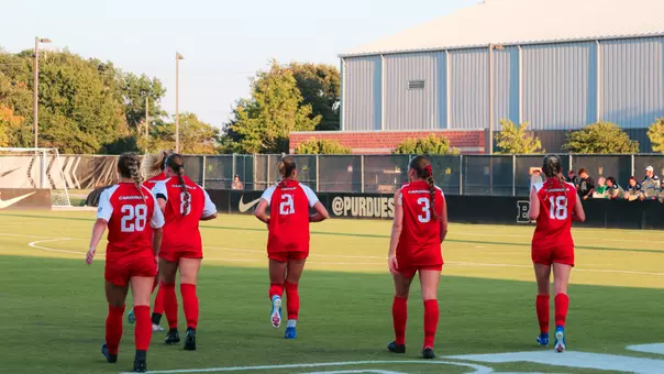 Soccer team in red uniforms runs on the field during Thursday night's match at Purdue