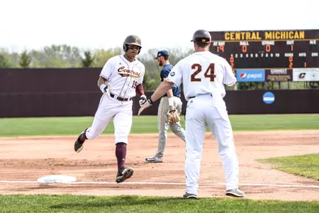 Sophomore Daniel Robinson (left) rounds third and gets a congratulatory handshake from third-base coach Doug Sanders on Wednesday during CMU's 4-3 nonconference victory over Michigan. Robinson hit his first career home run in the game.