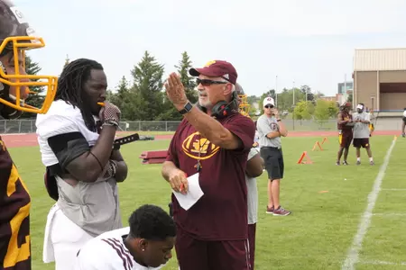 Defensive coordinator Greg Colby (right) talks with middle linebacker Malik Fountain during a CMU football practice.