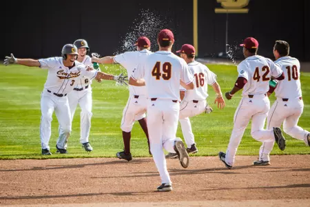 CMU players rush to greet Zach Heeke (3) after Heeke's ninth-inning single brought home the winning run in the Chippewas' dramatic 3-2 victory over Ohio on Thursday at Keilitz Field at Theunissen Stadium.