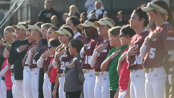 CofC softball players lined up on the field for the national anthem