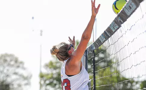 Beach Volleyball player jumps at the net to block