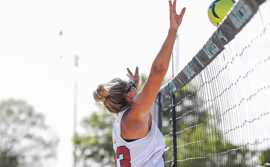 Beach Volleyball player jumps at the net to block