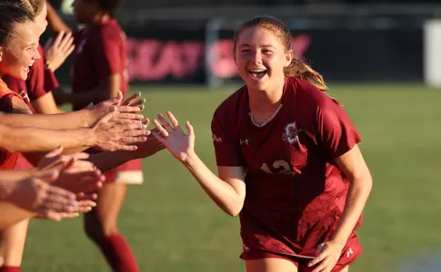 Emma Stankunas running through the starting lineup line and smiling