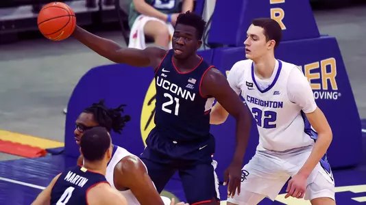 Jan 23, 2021; Omaha, Nebraska, USA;  Connecticut Huskies forward Adama Sanogo (21) grabs a pass against Creighton Bluejays center Ryan Kalkbrenner (32) in the second half at CHI Health Center Omaha. Mandatory Credit: Steven Branscombe-USA TODAY Sports