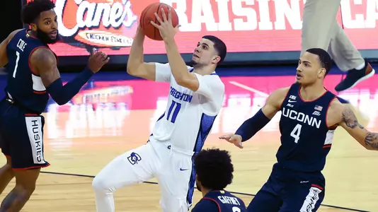 Jan 23, 2021; Omaha, Nebraska, USA;  Creighton Bluejays guard Marcus Zegarowski (11) scores against Connecticut Huskies guard Tyrese Martin (4) and guard Jalen Gaffney (0) in the second half at CHI Health Center Omaha. Mandatory Credit: Steven Branscombe-USA TODAY Sports