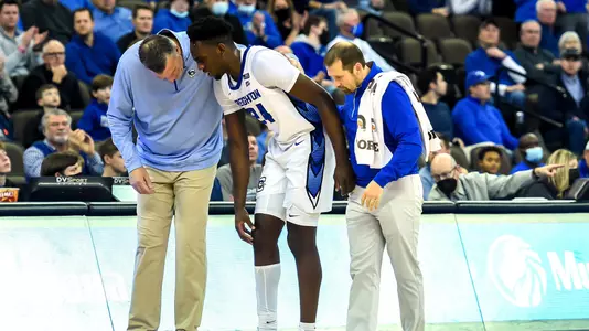 Athletic Trainer Ben McNair helps Arthur Kaluma off the court
