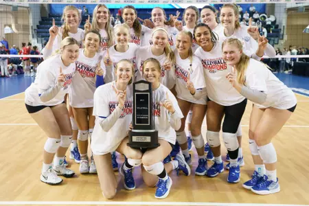The Creighton volleyball team poses around the BIG EAST regular season championship trophy.