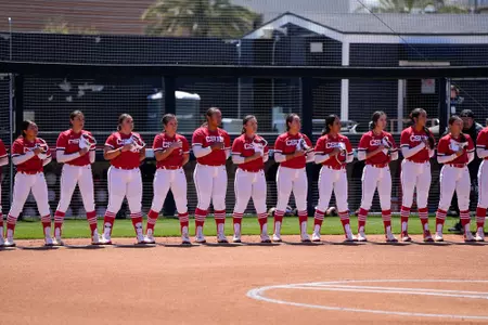 Softball team standing as the National Anthem plays before the game.