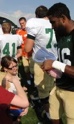 S Trent Matthews signs a football for young fans.