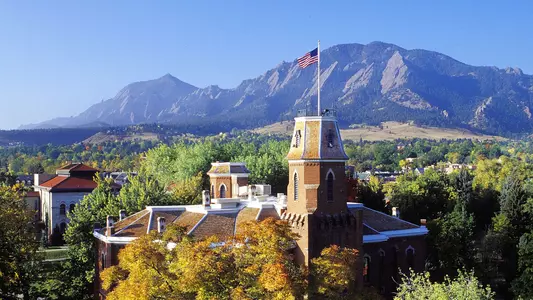 old main during the fall on CU's campus with the flatirons in the background
