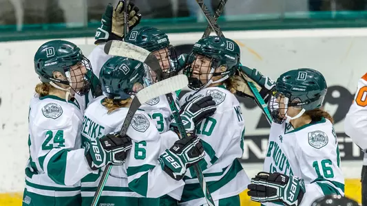 Women's hockey players celebrate after a goal