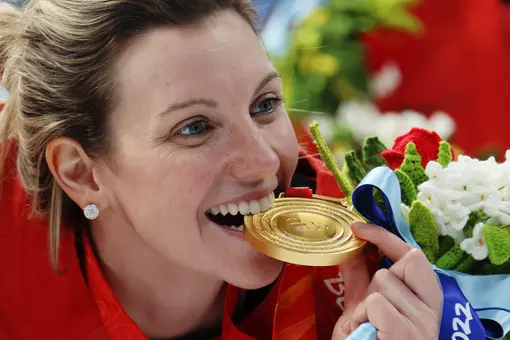 Laura Stacey ’16 bites her gold medal at the 2022 Winter Olympics