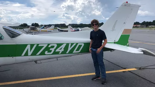 Davis Golick poses with a plane on the runway