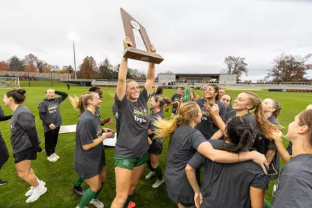 Women's soccer holding up ivy trophy
