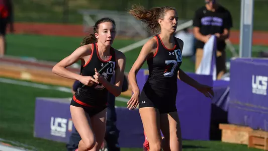 Photo of Sophia Mills and Julia Sirvinskas handing off the baton in the 4x80 meter relay