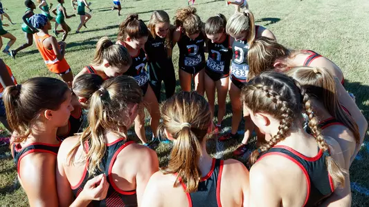 A photo of the women's cross country team in a huddle