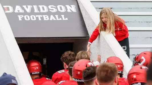 A young football fan high fives the team above the tunnel