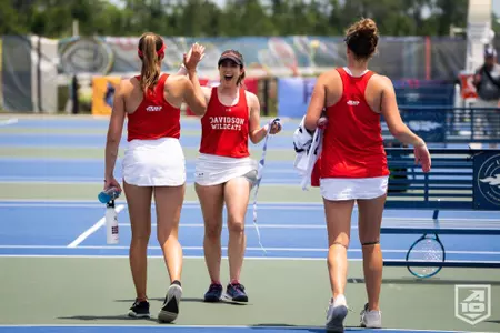 Daniela Porges greets Savanna Kollock and Josie Schaffer with a high-five at the A-10 Tournament
