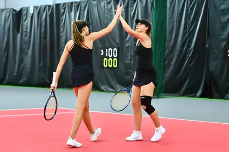 Josie Schaffer and Savanna Kollock high five after a point against Gardner-Webb on 4/7/23