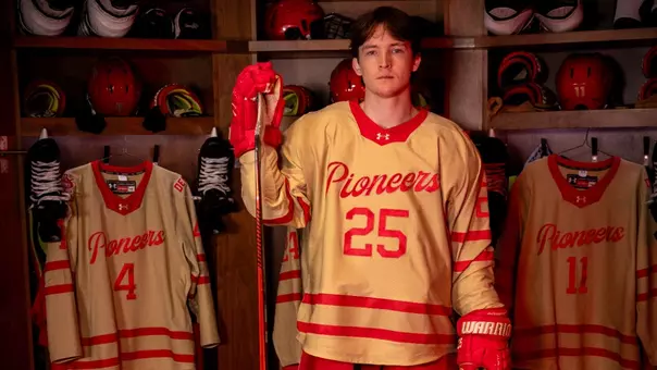 Clarke Caswell modeling DU hockey's Golden Age third jersey for the 2025-26 season.