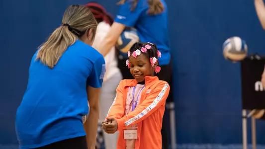 DePaul Volleyball player teaches young child how to pass