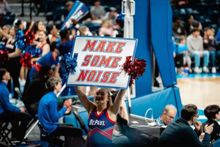 DePaul Cheerleader holding a sign that reads "Make Some Noise"