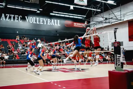 Audrey Klemp pushing volleyball past two blockers