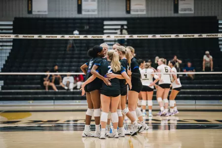 DePaul volleyball huddles on the court at Milwaukee