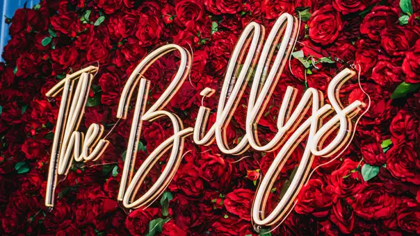 rose covered photo backdrop with a light up sign that says "The Billys"