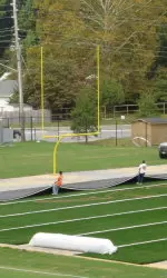 Workers are in the final stages of putting down a new synthetic surface on ECU's practice field.