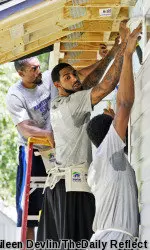 From left to right: East Carolina men's basketball Paris Roberts-Campbell, Terry Whisnant, and BJ Tyson work on the siding of a home with Habitat for Humanity on July 17, 2014. (Aileen Devlin/ The Daily Reflector)