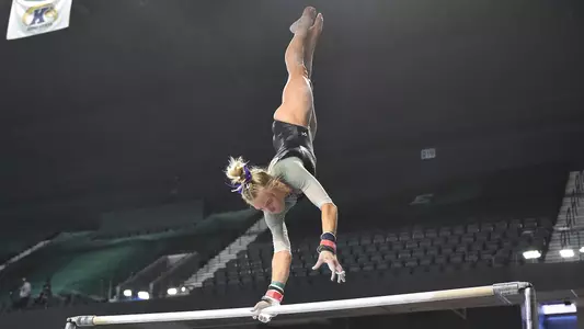 AG McCullough twists during handstand on bars against Kent State