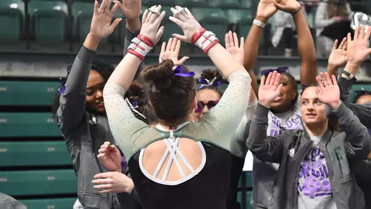 Hannah Hartung gets high fives from teammates after Kent State bars routine