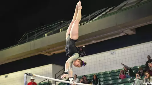 Kyrie Lowe twists during handstand in Kent State bars routine