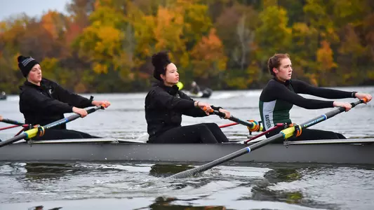 Caitlin Cleypool, Ariel Sutton and Emma Wyss rowing in an eight boat on Ford Lake