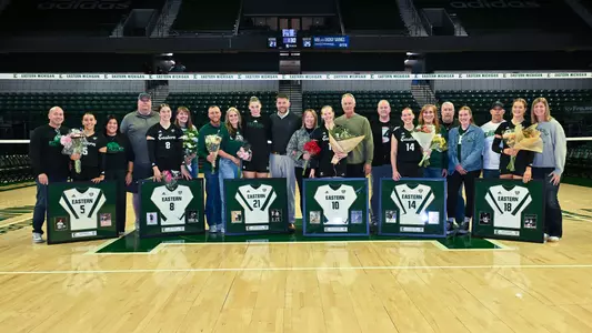 2025 EMU volleyball senior classes poses with their framed jerseys, flowers, and family members on 2025 senior night, Nov. 7