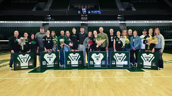 2025 EMU volleyball senior classes poses with their framed jerseys, flowers, and family members on 2025 senior night, Nov. 7