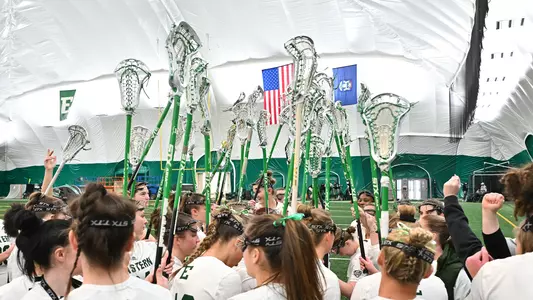 Lacrosse sticks are held in the air in a team huddle ahead of the Eagles' game with Butler