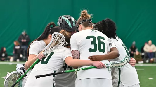 Lacrosse players huddle on the field to chat before the start of the game